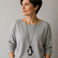 Pinguin-Pulloverkette an einer KI-generierten Frau mit grauem Pullover