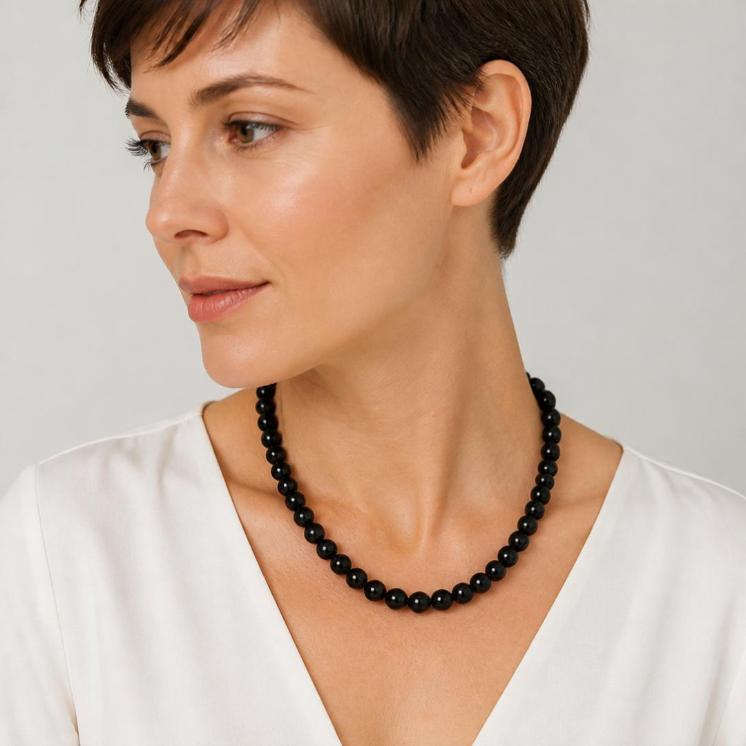 KI-Tragebild, 50 cm: Schwarze 10-mm-Perlenkette in 50 cm an einer KI-generierten Person, Trageansicht