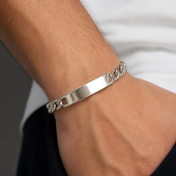 KI-generierter Mann trägt ein silberfarbenes Edelstahl-Schildband-Armband mit Flachpanzerkette und blanker Gravurplatte zu einem hellen Oberteil.