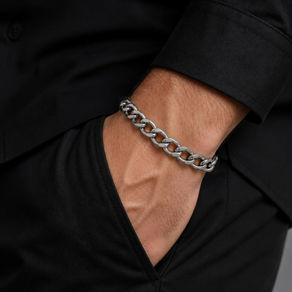 KI-generierter Mann trägt ein silberfarbenes Flachpanzerarmband am Handgelenk zu schwarzer Kleidung, mit der Hand in der Hosentasche.