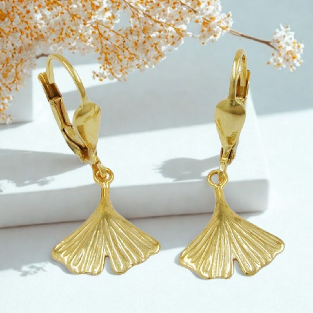 Ginkgoblatt Ohrhänger 9 Karat Gold auf weißem Podest mit Kirschblüten-Hintergrund