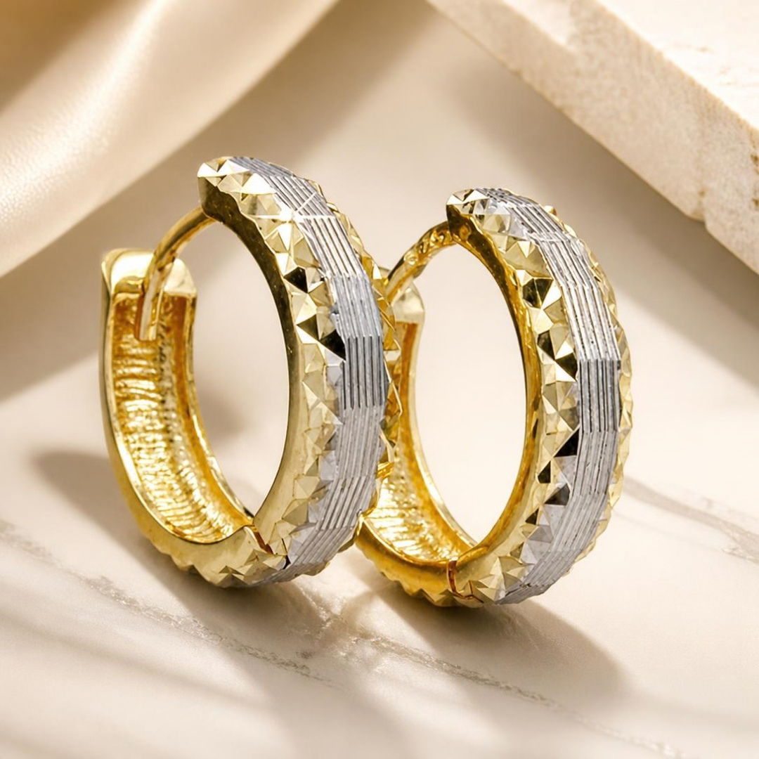 Bicolor-Creolen aus 9 Karat Gold vor dekorativem Hintergrund