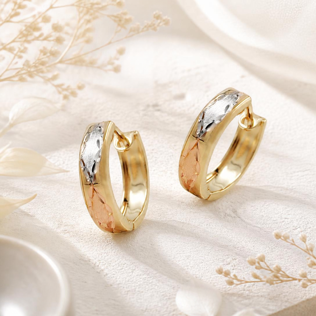 Tricolor-Creolen mit Rhomben aus 9 Karat Gold vor dekorativem Hintergrund