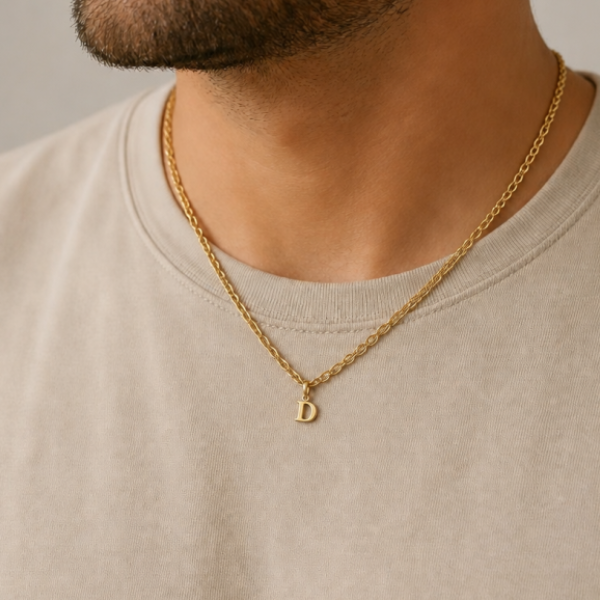 KI-generierter Mann trägt einen goldfarbenen D-Anhänger an einer Kette zu einem hellen T-Shirt.
