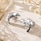 Glänzende Delfin-Ohrstecker aus Silber 925 auf hellem Stein mit dezenter weißer Blütendekoration